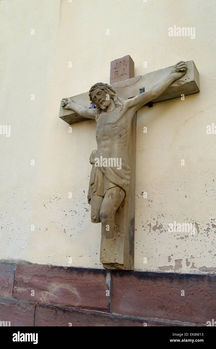 Dañado estatua de Jesús en la cruz sin piernas en una pared de la iglesia en la región de Alsacia, Francia Foto de stock