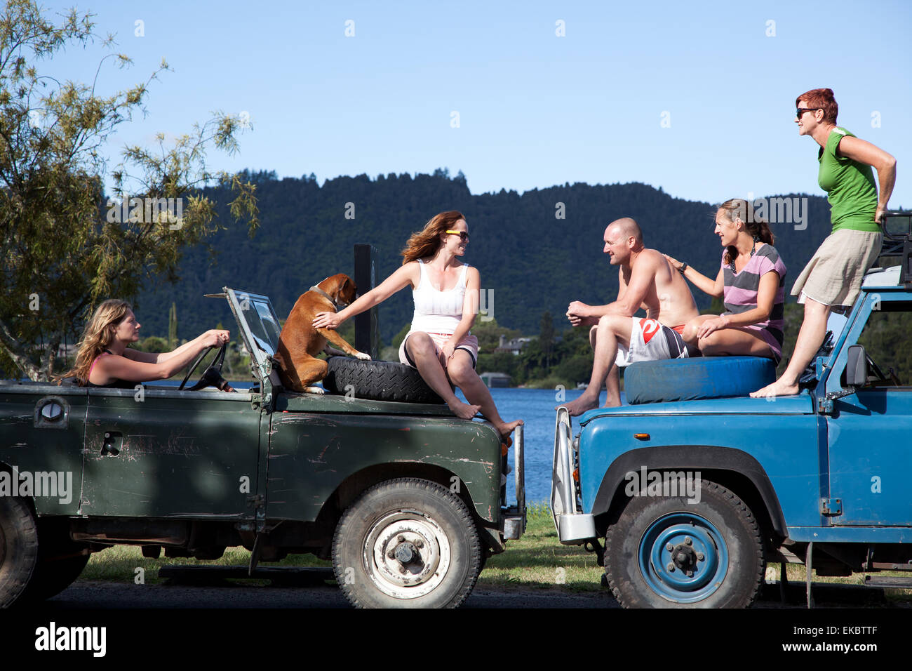Amigos adultos conversando en la parte superior de vehículos off road, Lake Okareka, Nueva Zelanda Foto de stock