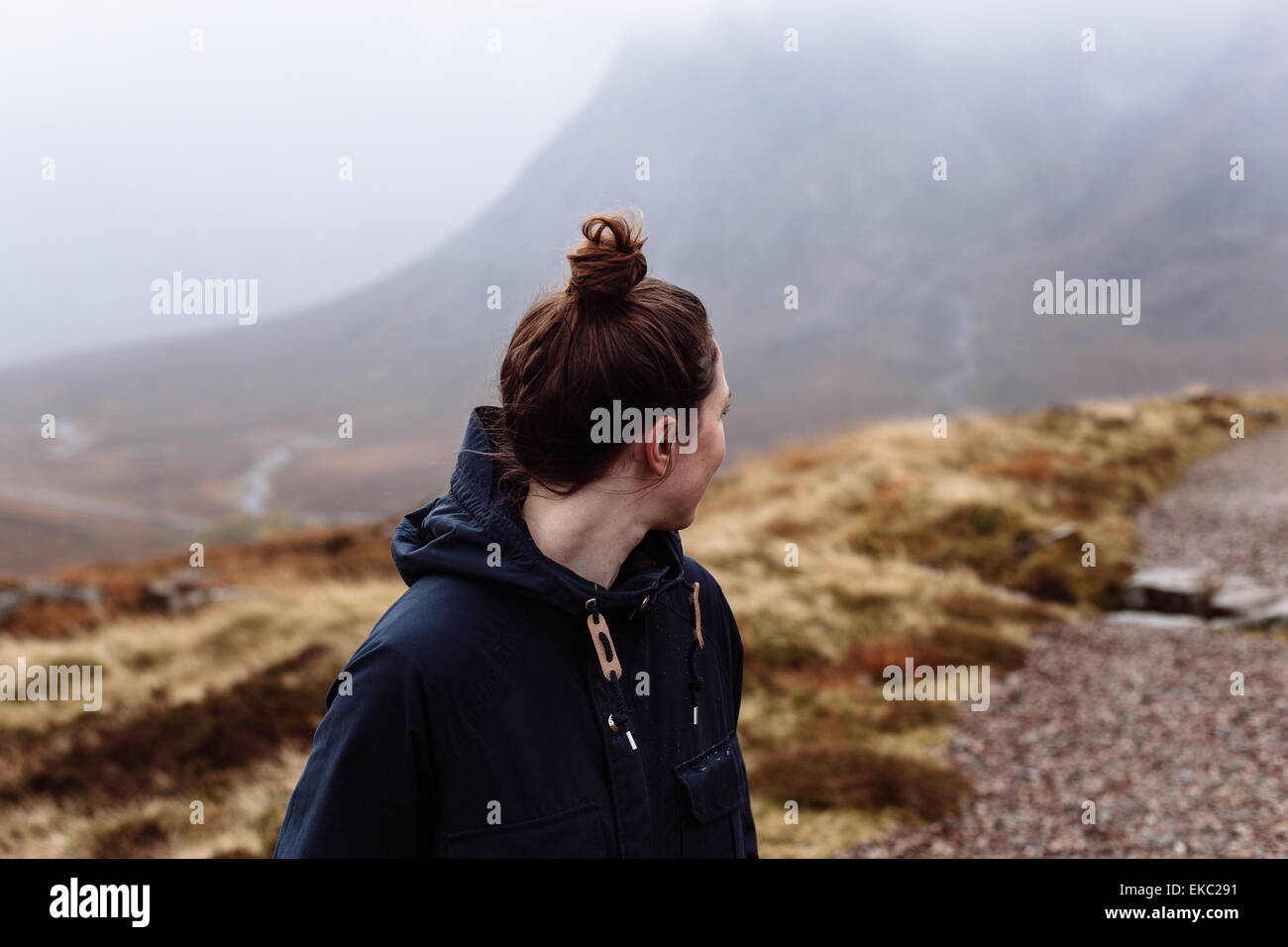 Mujer mirando por encima del hombro hacia las montañas Foto de stock