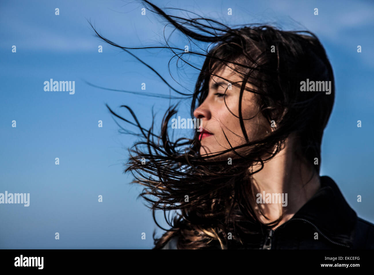 Mujer joven busca lateralmente con pelo en el viento Foto de stock