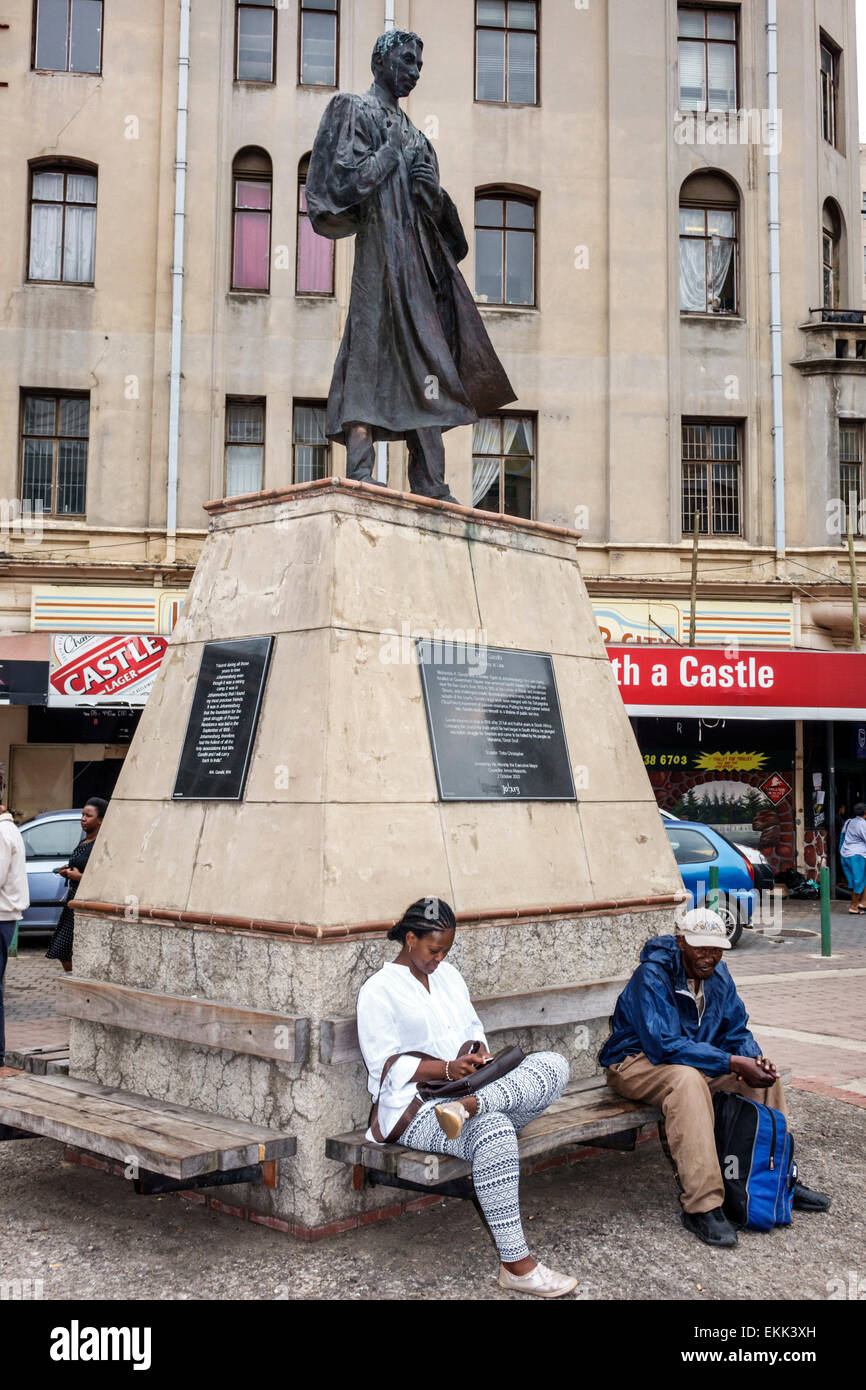 Johannesburgo Sudáfrica,Gandhi Square,Mohandas Mahatma,abogado joven,estatua,mujer negra mujeres,hombre hombres hombres,residentes,sentada,SAfri150 Foto de stock
