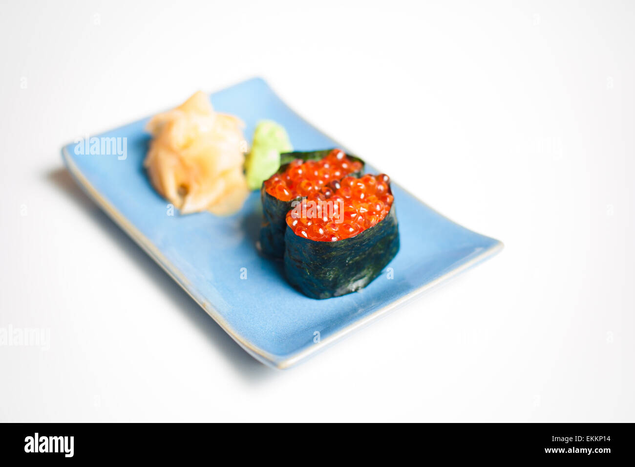 Sushi, Gunkan sobre placa azul con jengibre y wasabi, el enfoque selectivo y fondo blanco. Foto de stock