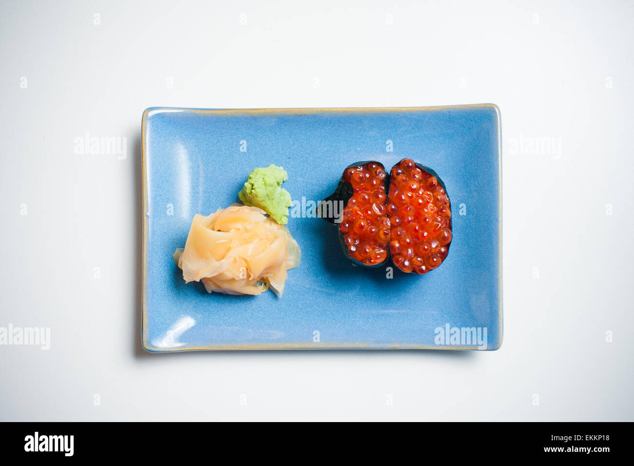Sushi, Gunkan sobre placa azul con jengibre y wasabi, fondo blanco. Foto de stock