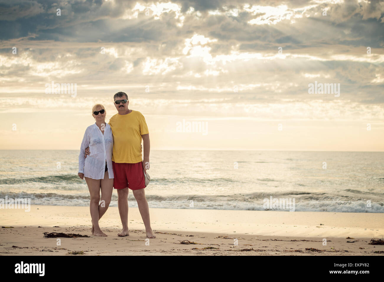 Feliz pareja madura a mediados de los cincuenta en la playa. Tonificación en colores cálidos y luz natural. Foto de stock