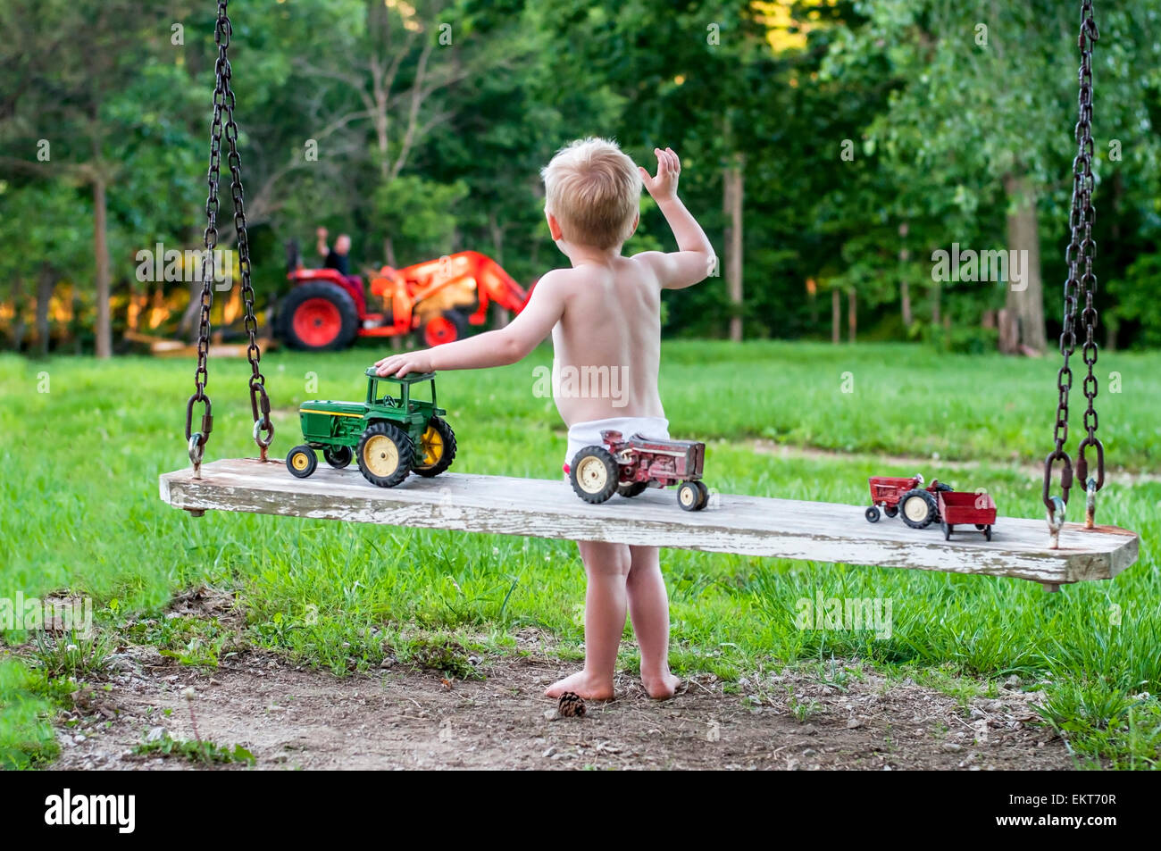 Boy ondeando al papá en el tractor Foto de stock