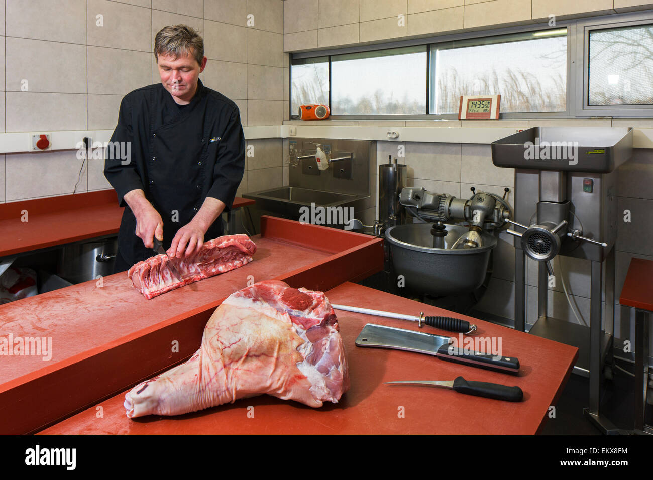 Carnicero / cortador de carne prepara primal cortes en una variedad de segmentos más pequeños para minoristas Foto de stock