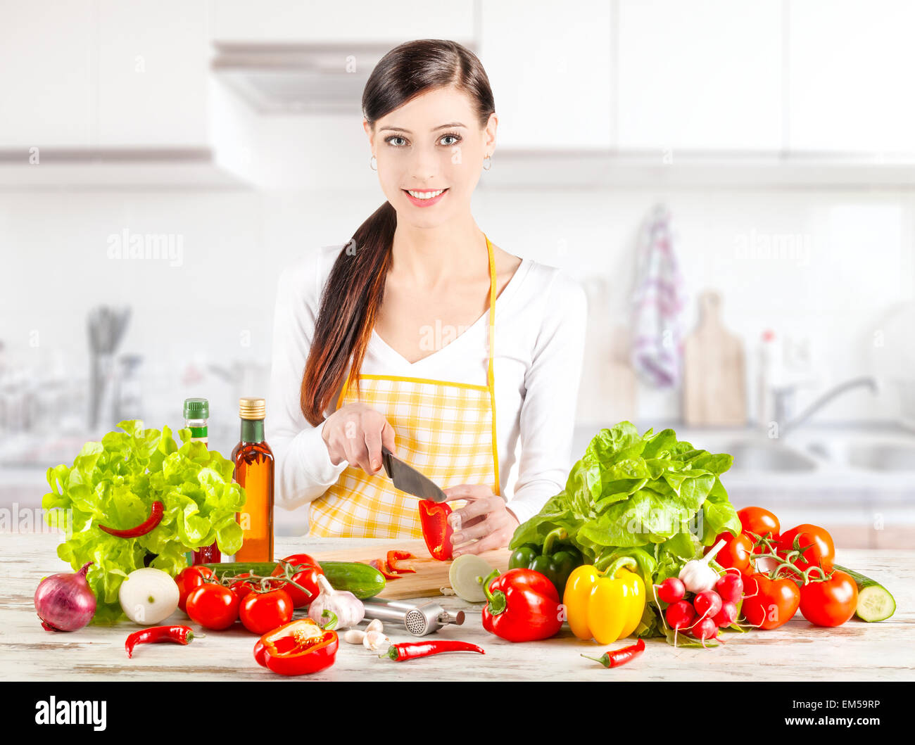 Mujer joven preparando ensalada en la cocina. La comida sana y la dieta concepto. Foto de stock