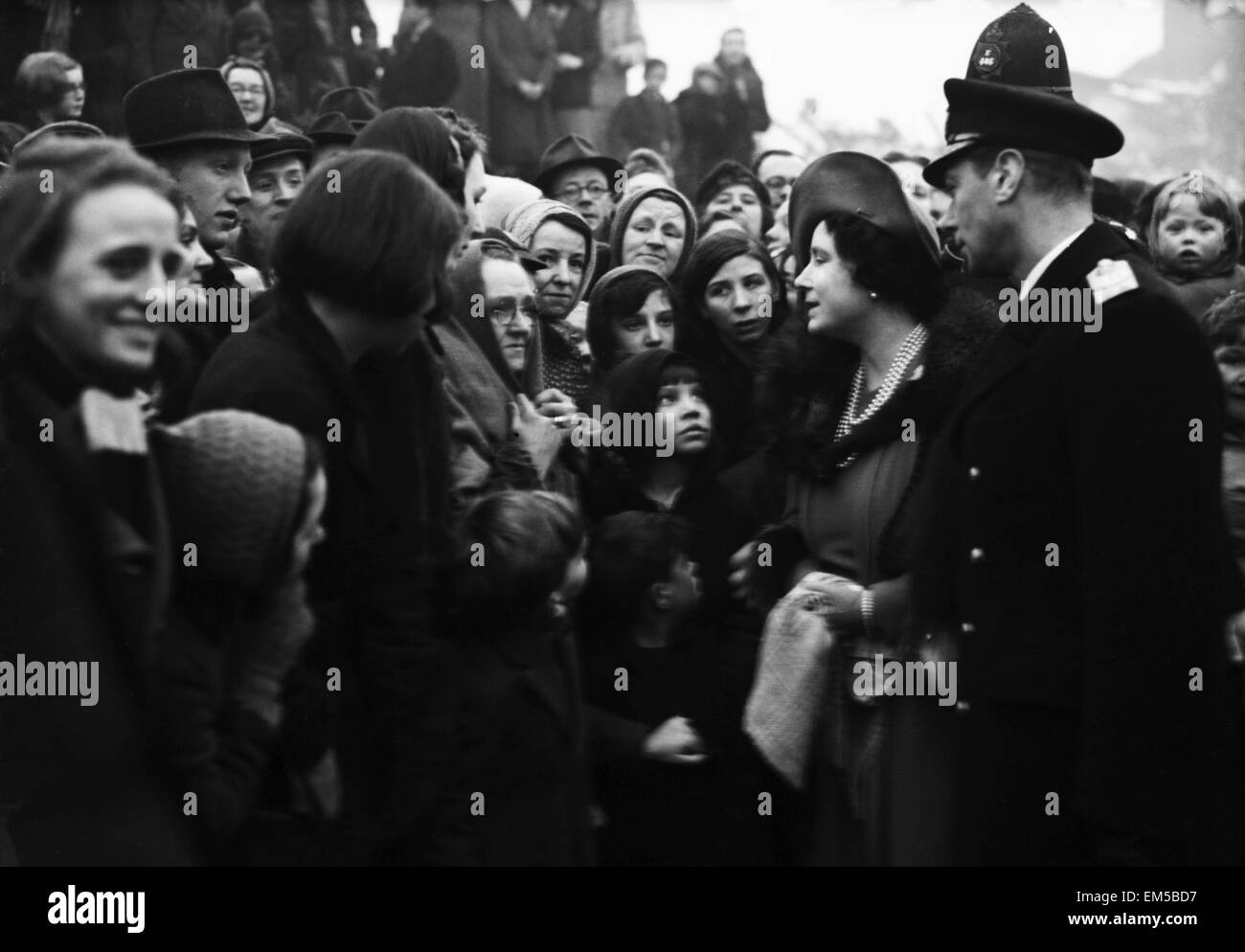 Queen Elizabeth vigilados por su marido el Rey George VI, habla a un grupo de personas que se han quedado sin hogar en una de las zonas fuertemente mosy asaltaron de Sheffield durante la guerra. El 6 de enero de 1941. Foto de stock