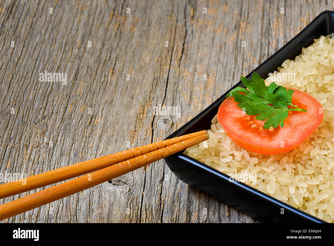 Placa con arroz crudo y la rodaja de tomate Foto de stock