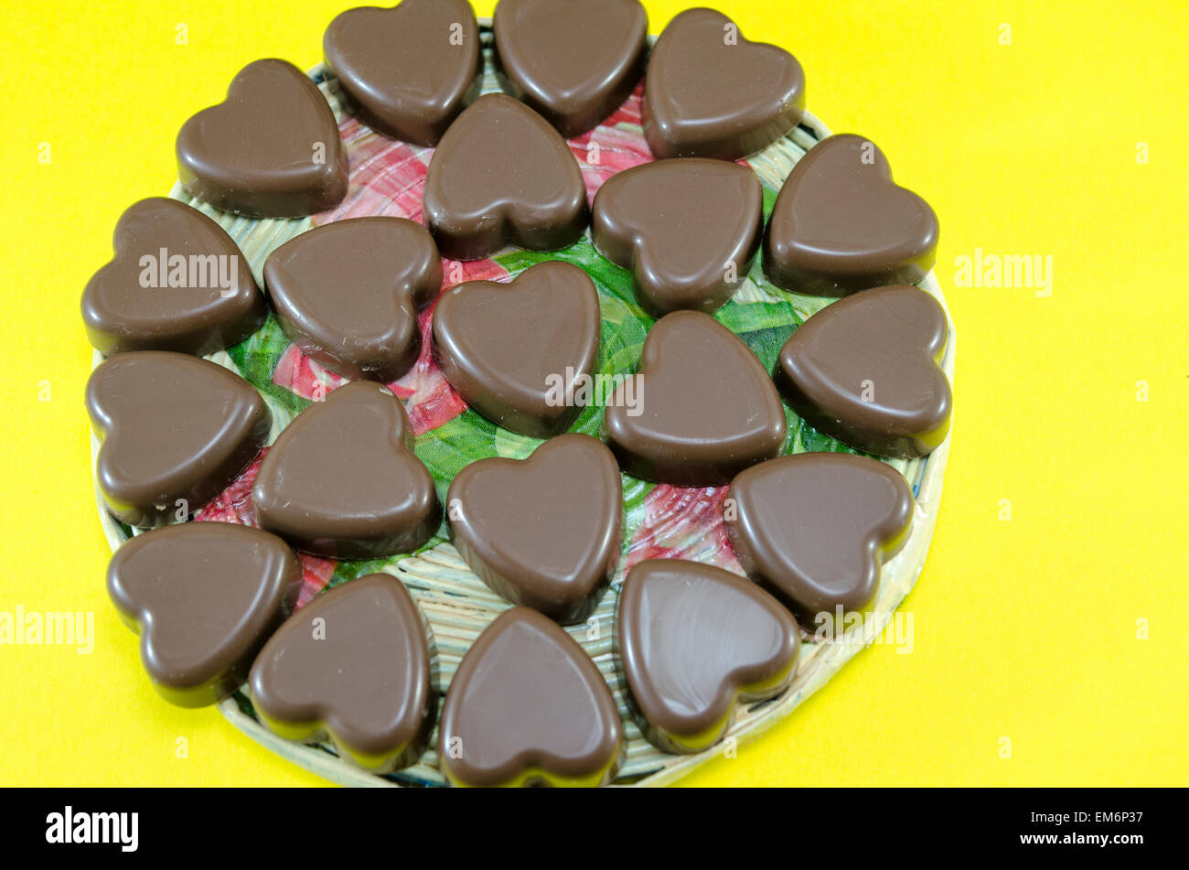 Deliciosamente buscando chocolate en forma de corazón sobre fondo amarillo Foto de stock