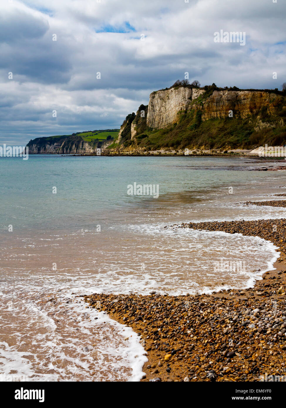 Olas rompiendo en la playa de guijarros en Seaton mirando al oeste hacia la cerveza Cove, en Devon, Inglaterra Foto de stock