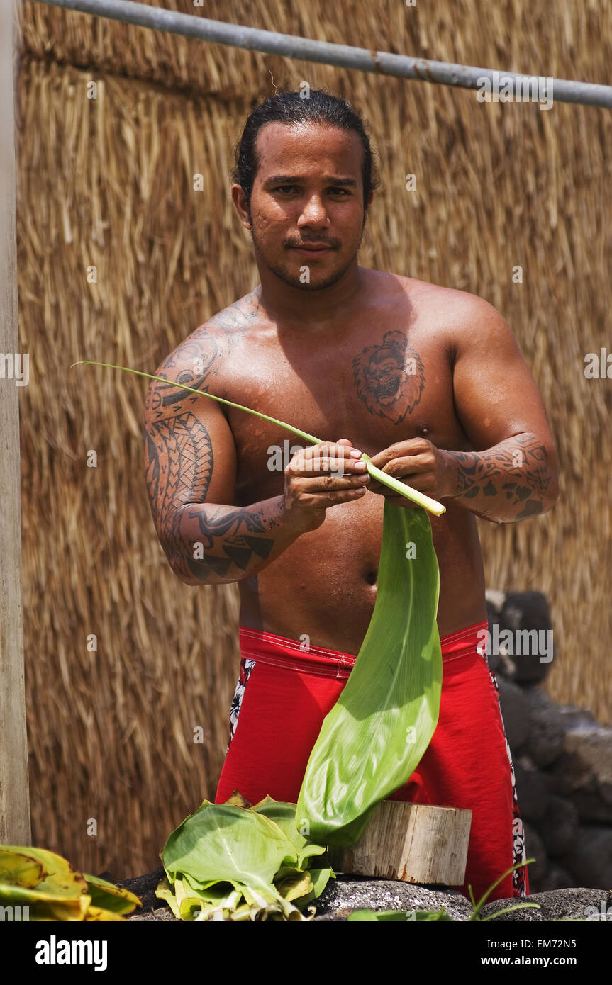 Hawaii, Isla Grande, Kailua-Kona, Ahu'ena Heiau, joven hombre hawaiano desvestido Ti deja para el Proyecto Cultural de la Comunidad. Foto de stock
