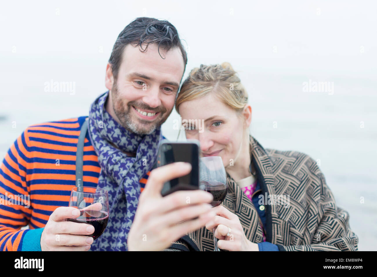 Pareja en la playa, bebiendo vino, teniendo autorretrato con el smartphone Foto de stock