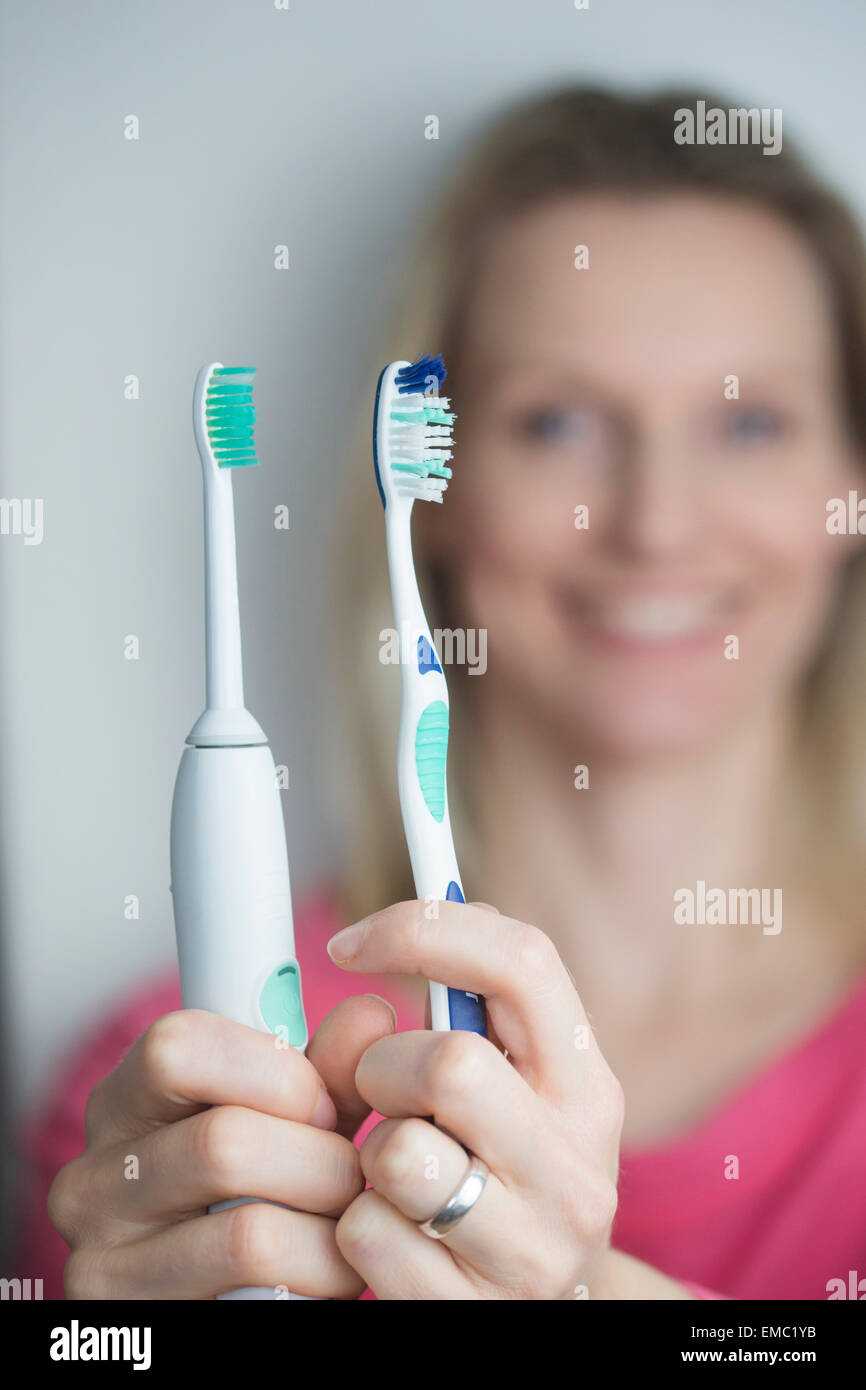 Mujer sosteniendo clásico y cepillo de dientes eléctrico Foto de stock
