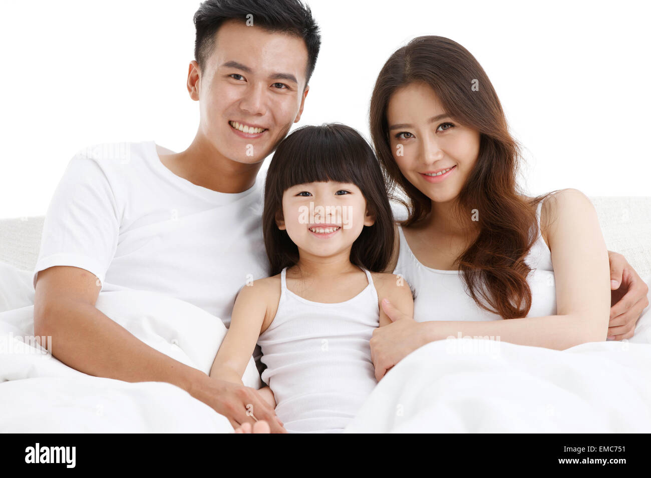 La felicidad de una familia de tres personas en la cama de la habitación. Foto de stock