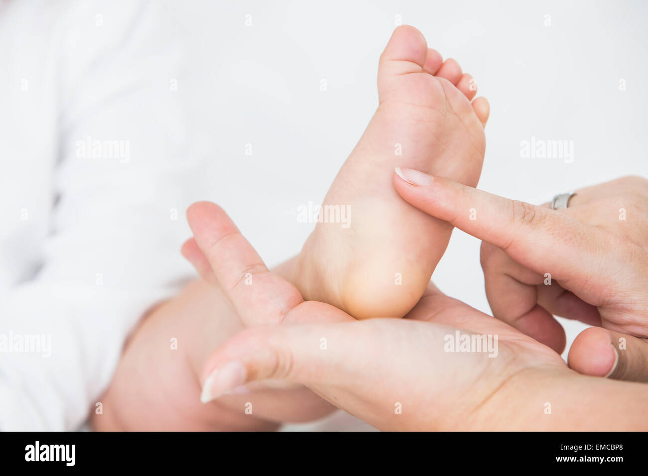 La mano de la madre cosquillas en la planta del pie del bebé. Foto de stock