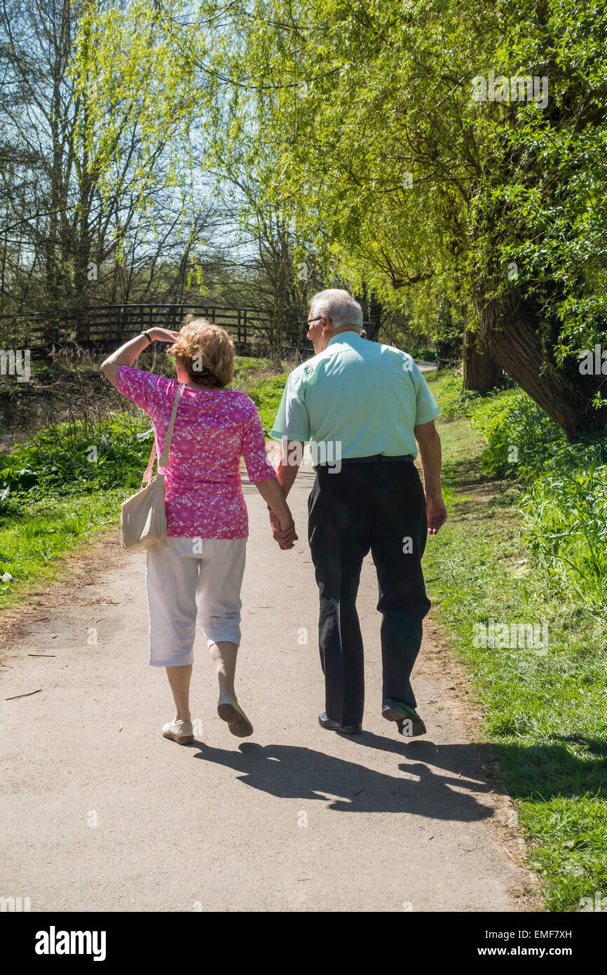 Pareja de ancianos caminando tomados de las manos Riverside país camine Foto de stock