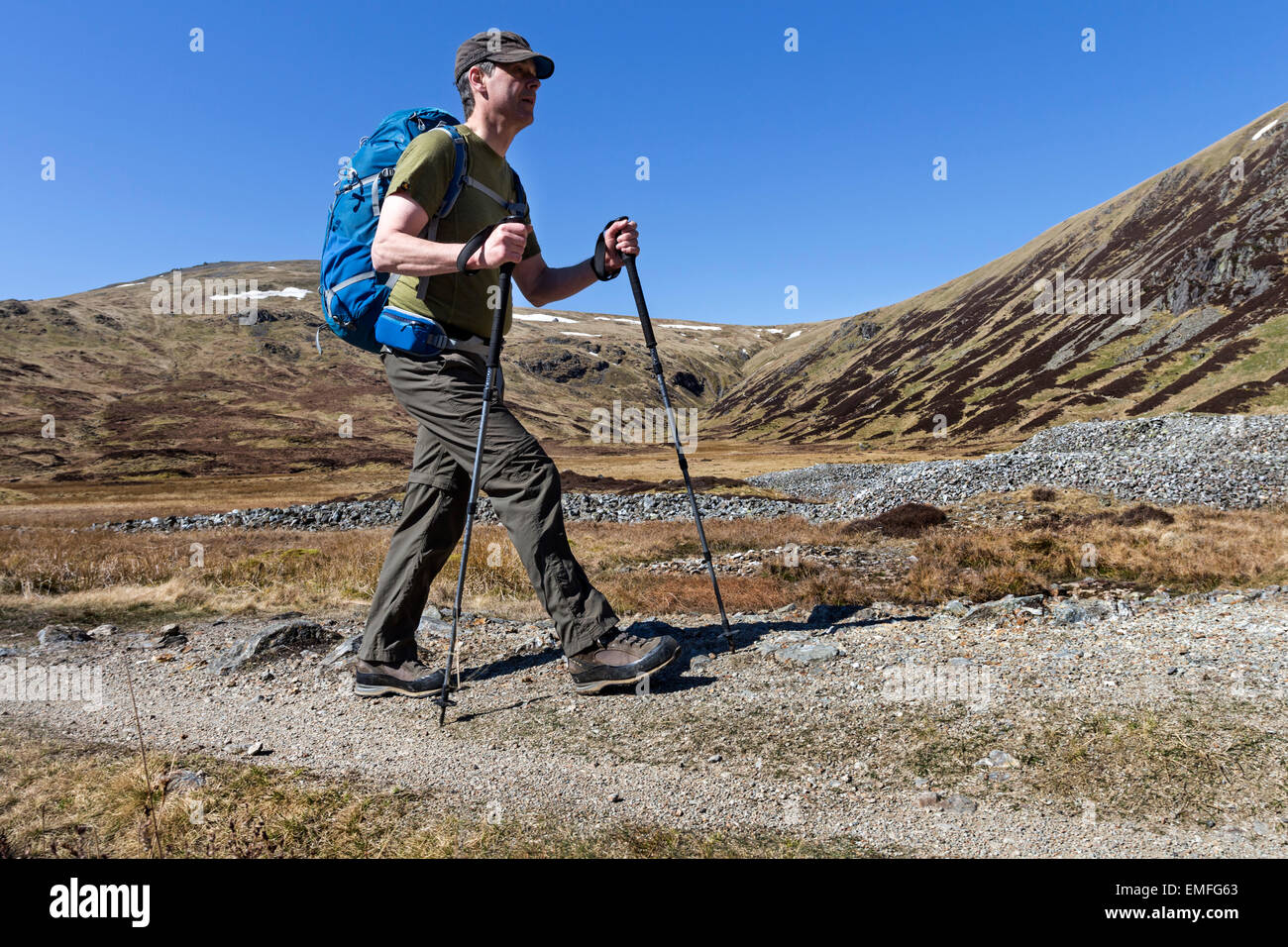 Walker utilizando bastones de caminar bajo un cielo azul sobre los palos  Gill Camino con palos pase en el fondo el Distrito del Lago (Cumbria  Fotografía de stock - Alamy