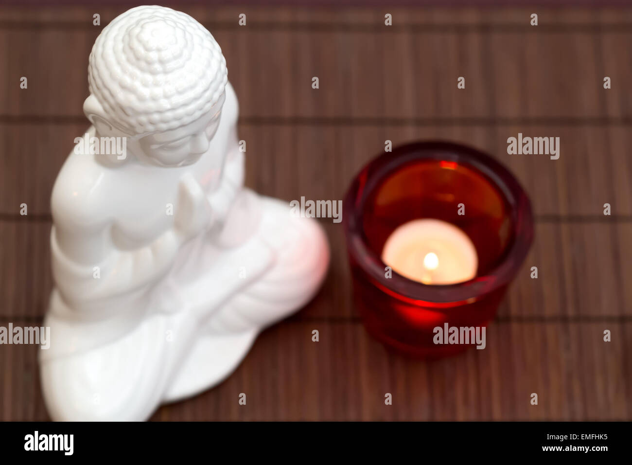 Figura blanca en pose de meditación con vela de cristal rojo desde arriba Foto de stock