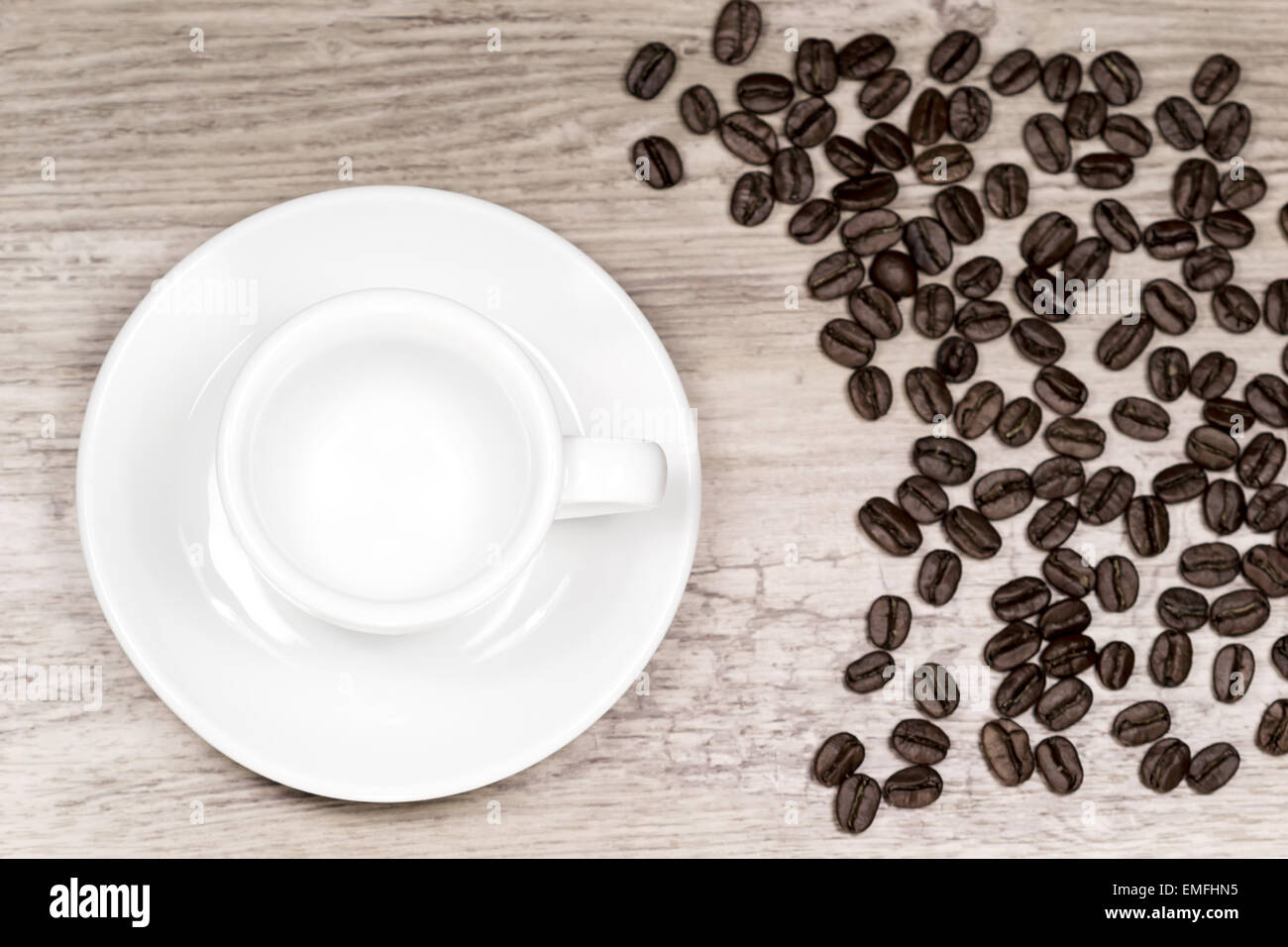 Limpiar vacía taza de café sobre la mesa de madera con fondo borroso y granos de café desde arriba Foto de stock