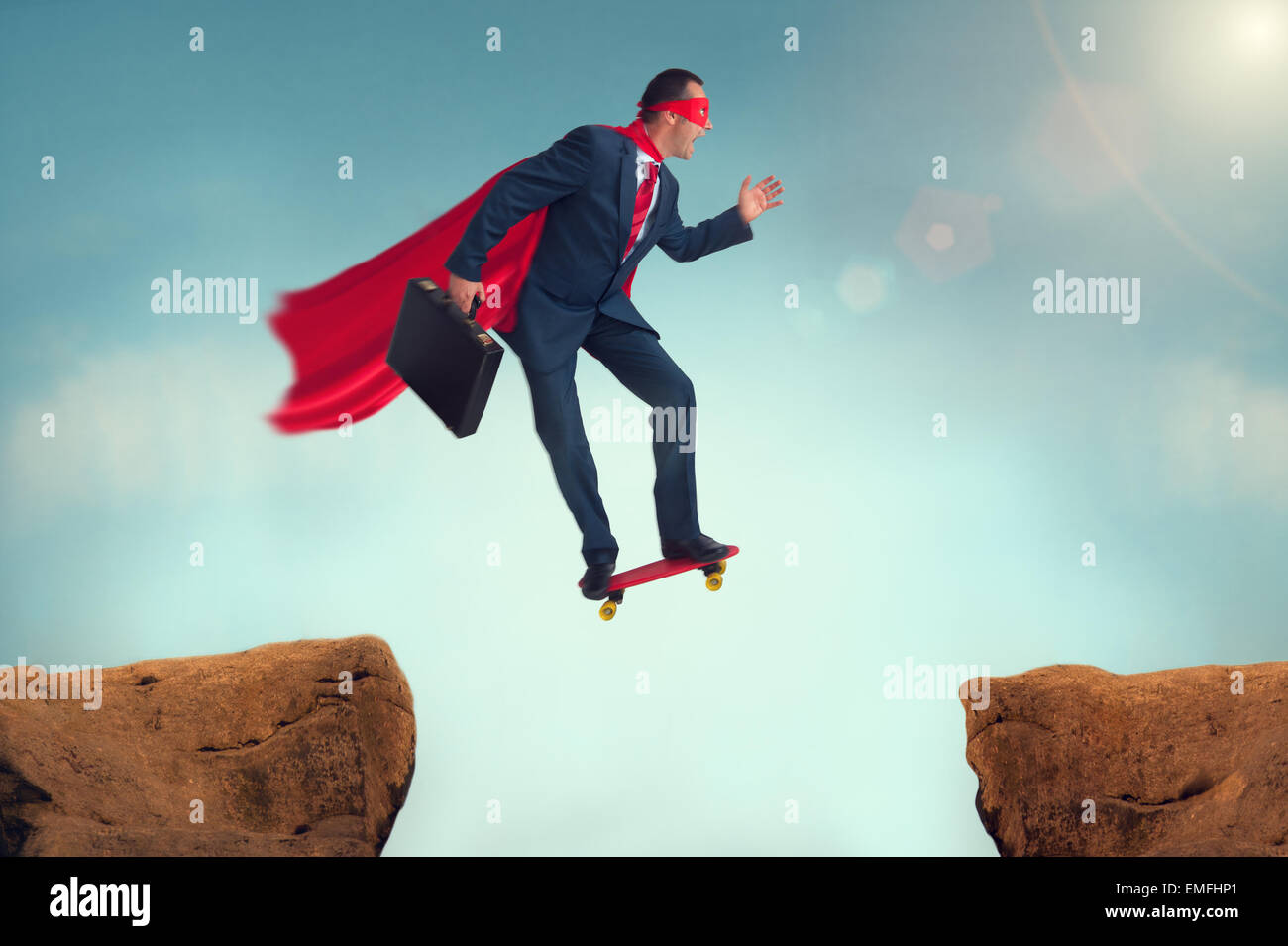 Superhéroe empresario desafío hacer un arriesgado salto de fe en un monopatín Foto de stock
