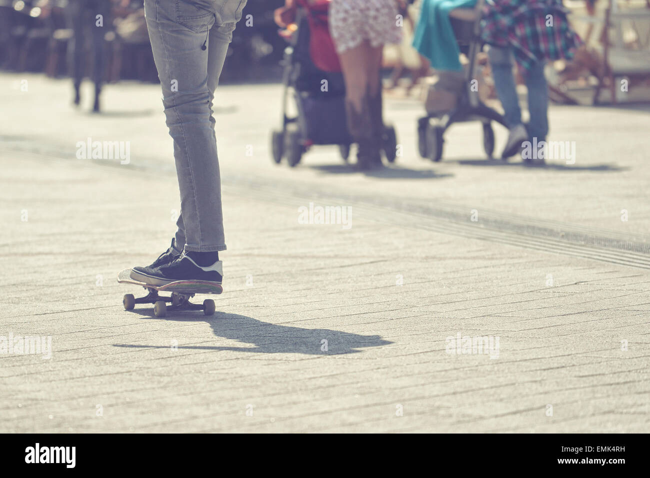 Macho joven skateboarder Skateboard Equitación en pavimento de las calles de la ciudad, el enfoque selectivo de la imagen en tonos de proceso cruzado Foto de stock