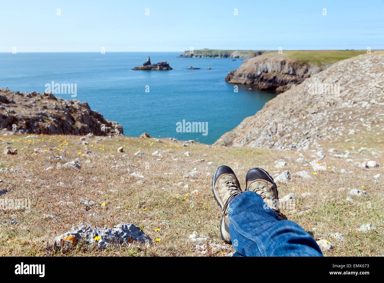 El hombre tendido en el suelo, frente al mar, descansando en la costa de Gales del Sur . Foto de stock