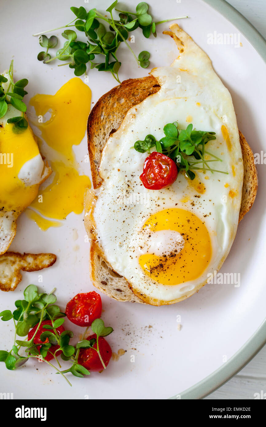 Desayuno, huevos sobre pan tostado con tomates cherry y berro Foto de stock