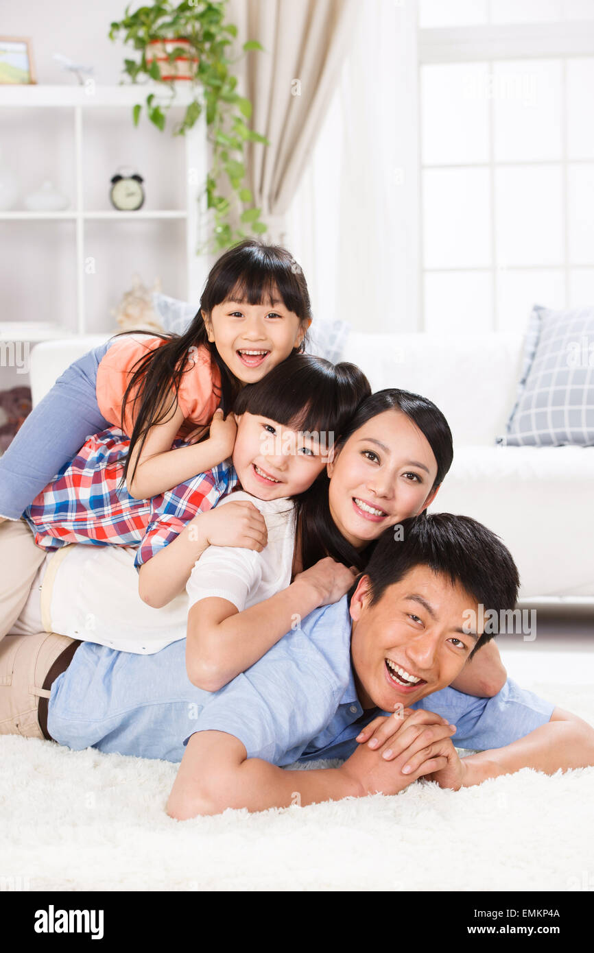 La felicidad de una familia de cuatro personas en la sala de estar jugando  en la alfombra Fotografía de stock - Alamy