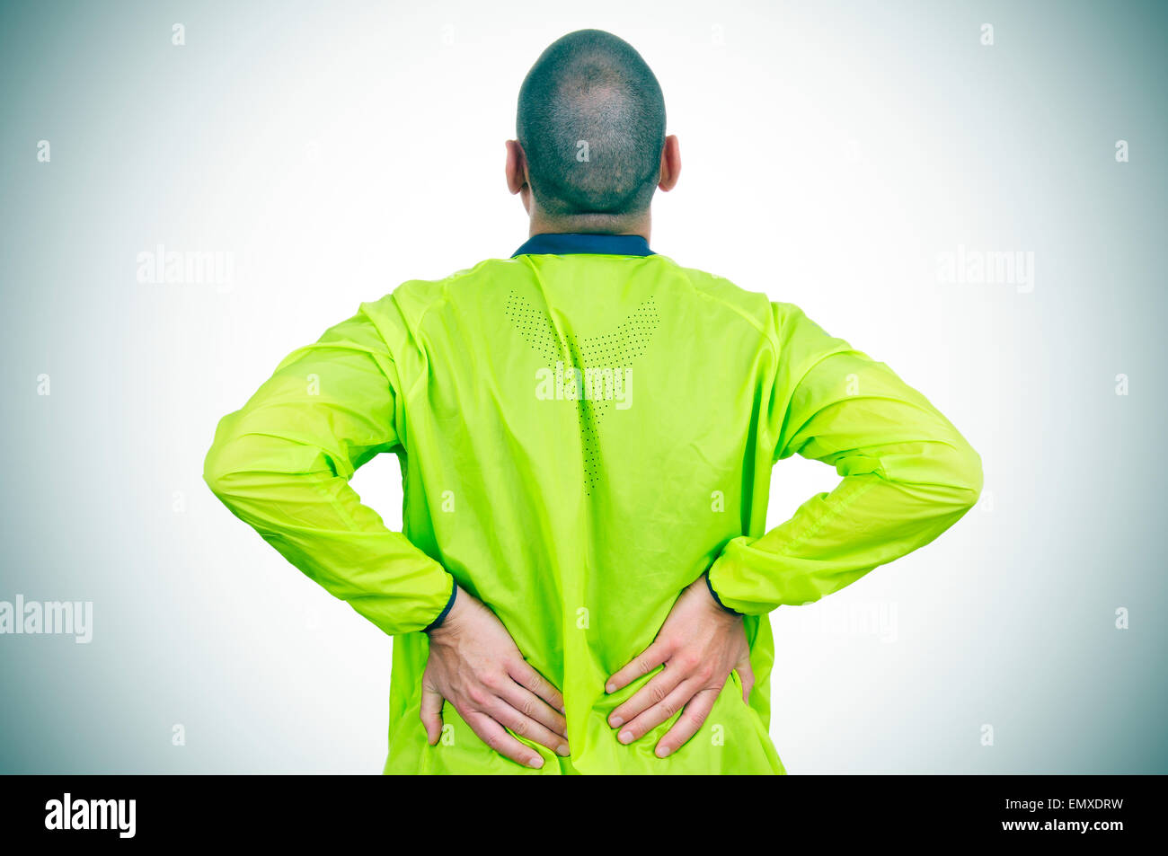 Un joven deportista caucásica vistiendo ropa deportiva con las manos en la espalda a causa de su dolor en la parte baja de la espalda Foto de stock
