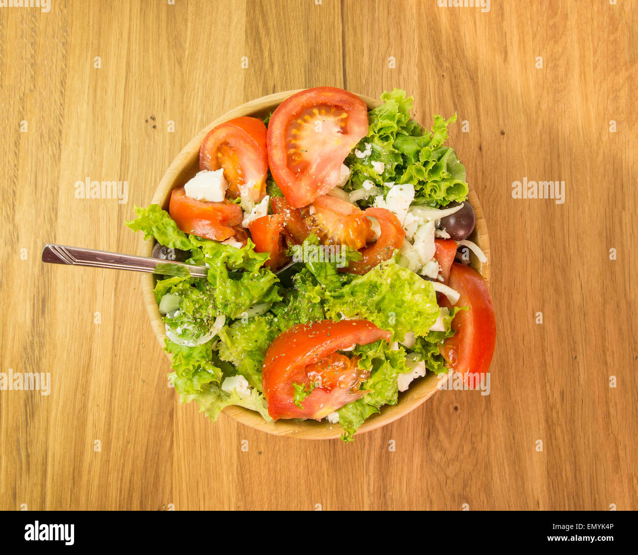 Ensalada griega - horquilla tomates lechuga cebolla en recipiente de madera Foto de stock