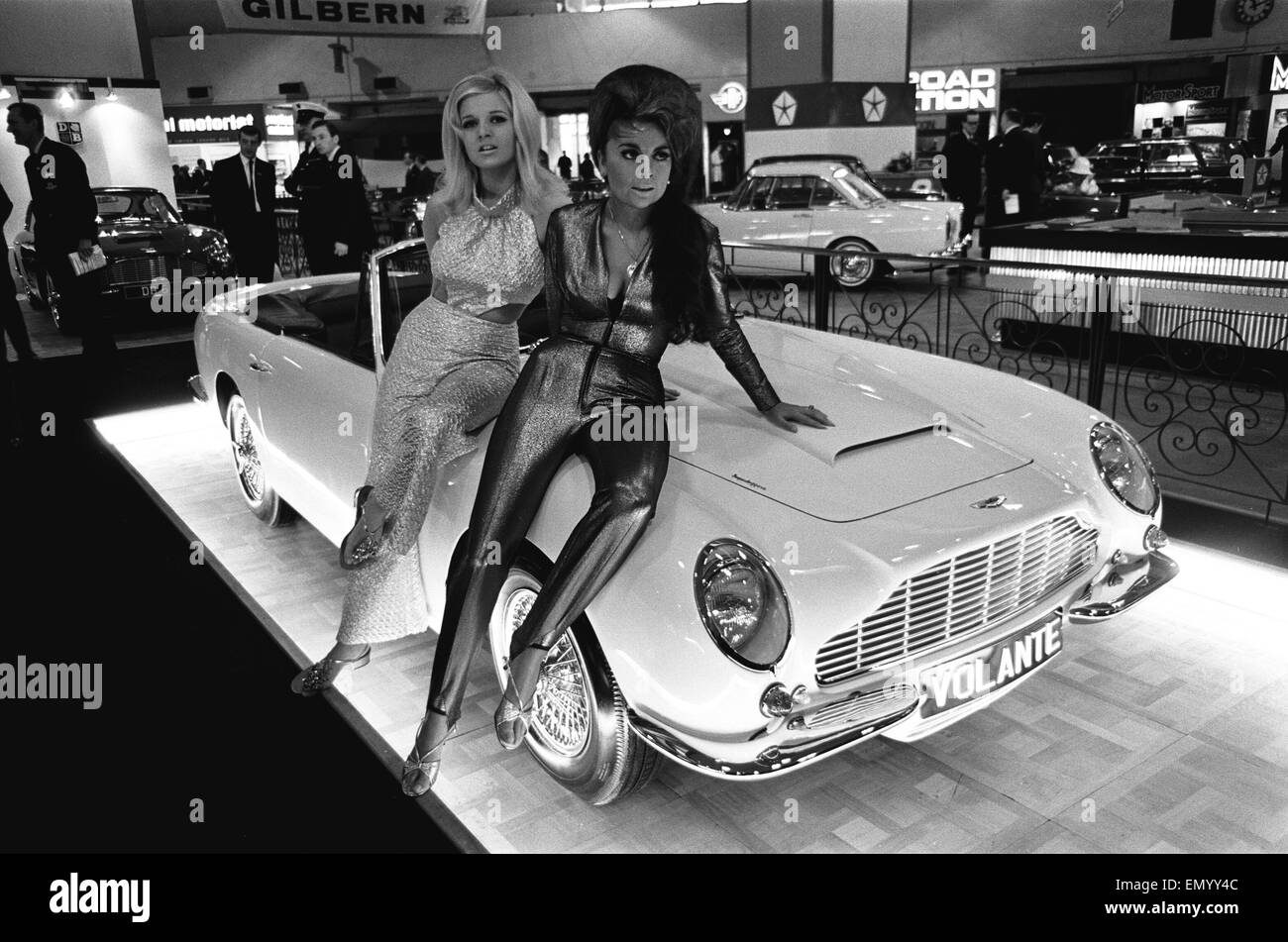 Modelos plantean sobre el capó de un Aston Martin Volante en Motor Show el 18 de octubre de 1966. Foto de stock