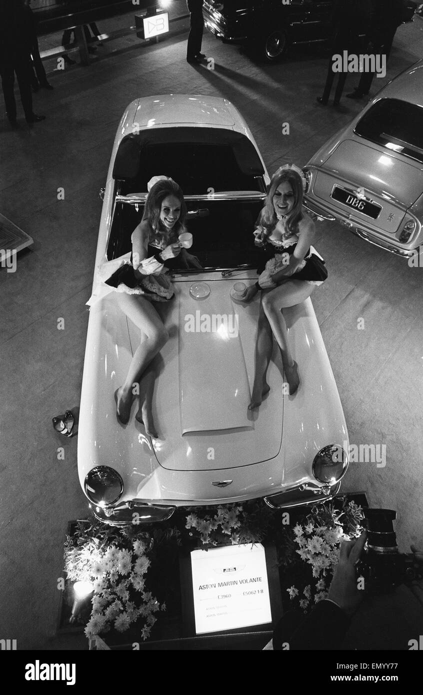Modelos plantean sobre el capó de un Aston Martin Volante en Motor Show el 15 de octubre de 1968. Foto de stock