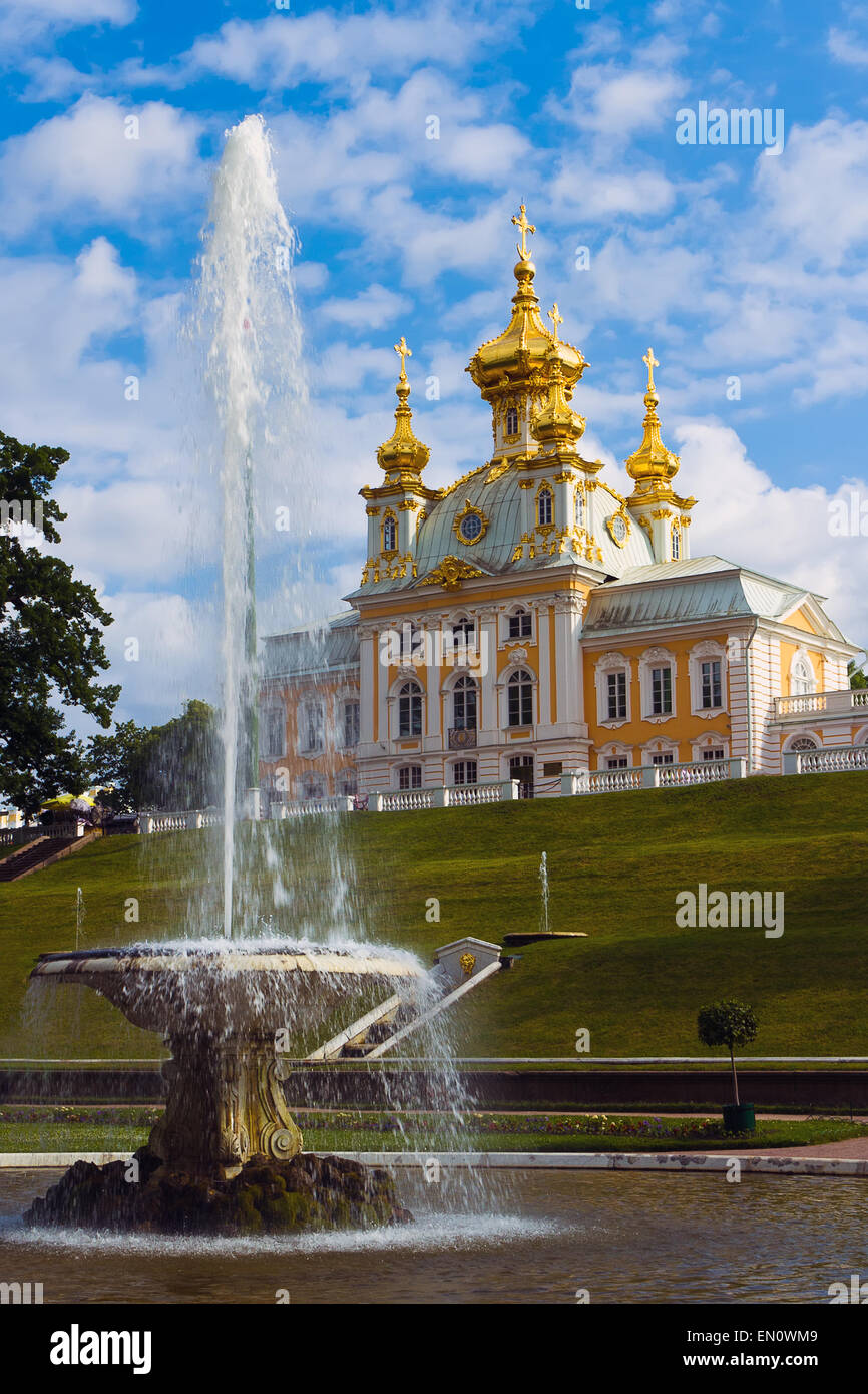 Un fontain y una iglesia contra el cielo azul. Peterhof, Rusia Foto de stock