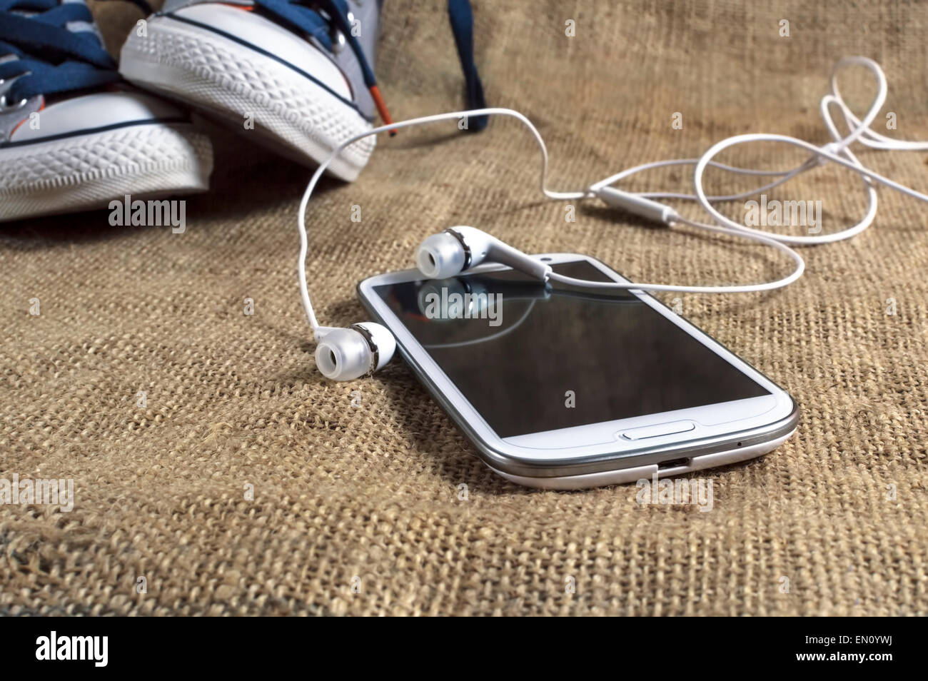 Teléfono inteligente sobre un mantel con sneakers. Profundidad de campo. Foto de stock