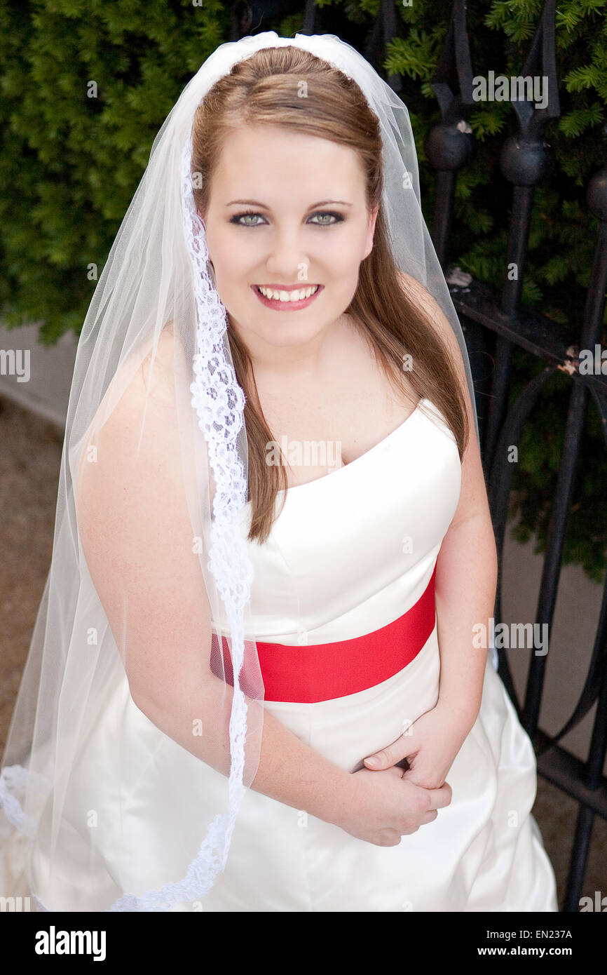 Novia en un vestido blanco, con una banda de color rojo brillante Fotografía stock