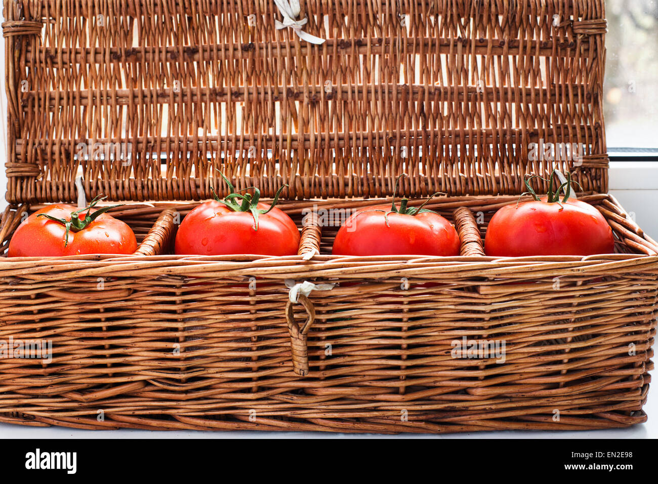 Cuatro tomates con rocío tumbado por separado en mimbre cuadro retro Foto de stock