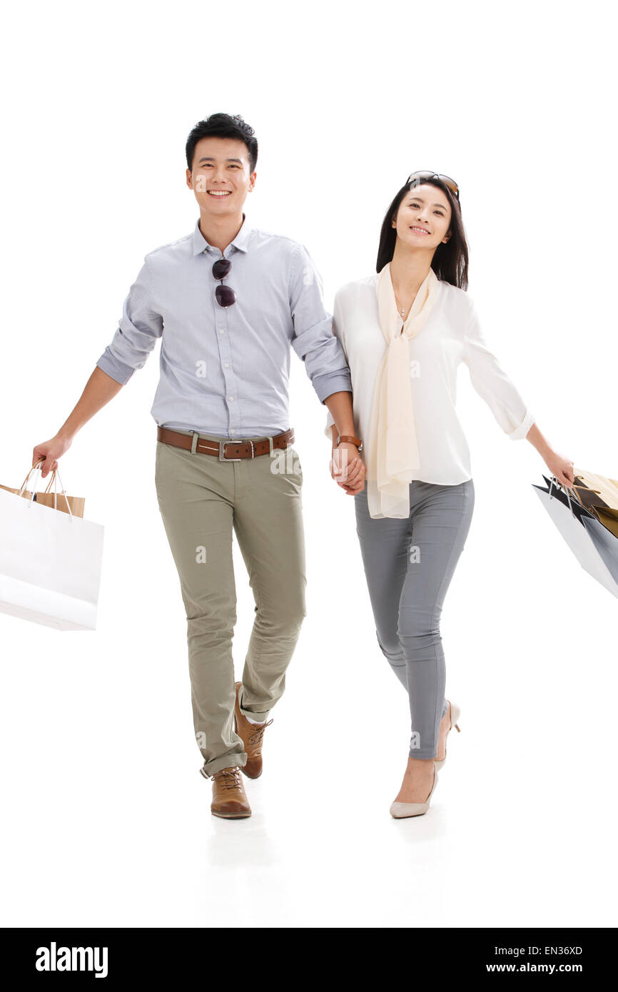 La joven pareja tomados de las manos con bolsas de la compra. Foto de stock