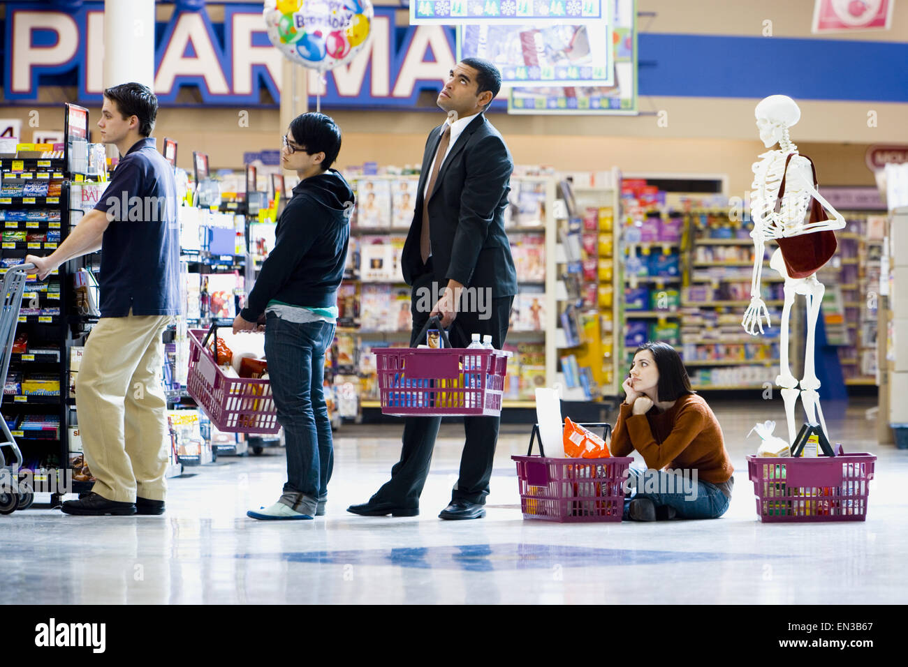 Cuatro personas y un esqueleto en el supermercado cartel Foto de stock