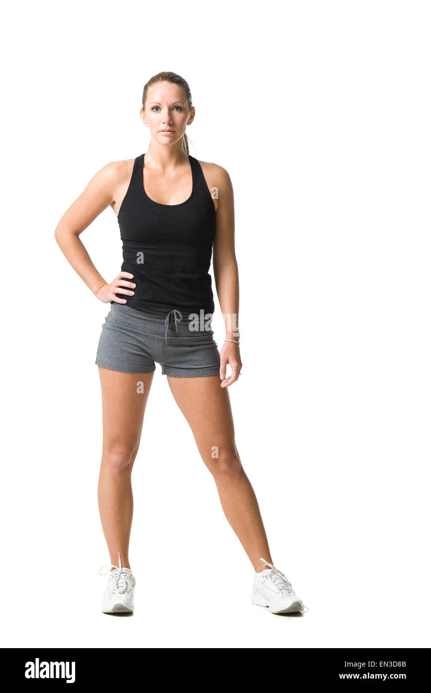 Retrato de estudio de joven mujer vistiendo ropa deportiva de pie con las manos en la cadera Foto de stock