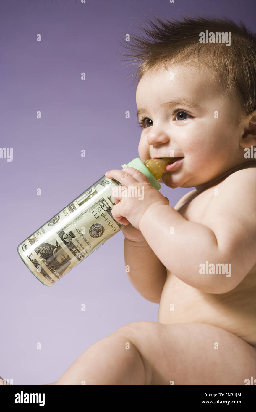 Bebé bebiendo de la botella con la moneda estadounidense en ella Foto de stock