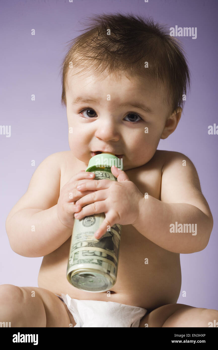 Bebé bebiendo de la botella con la moneda estadounidense en ella Foto de stock