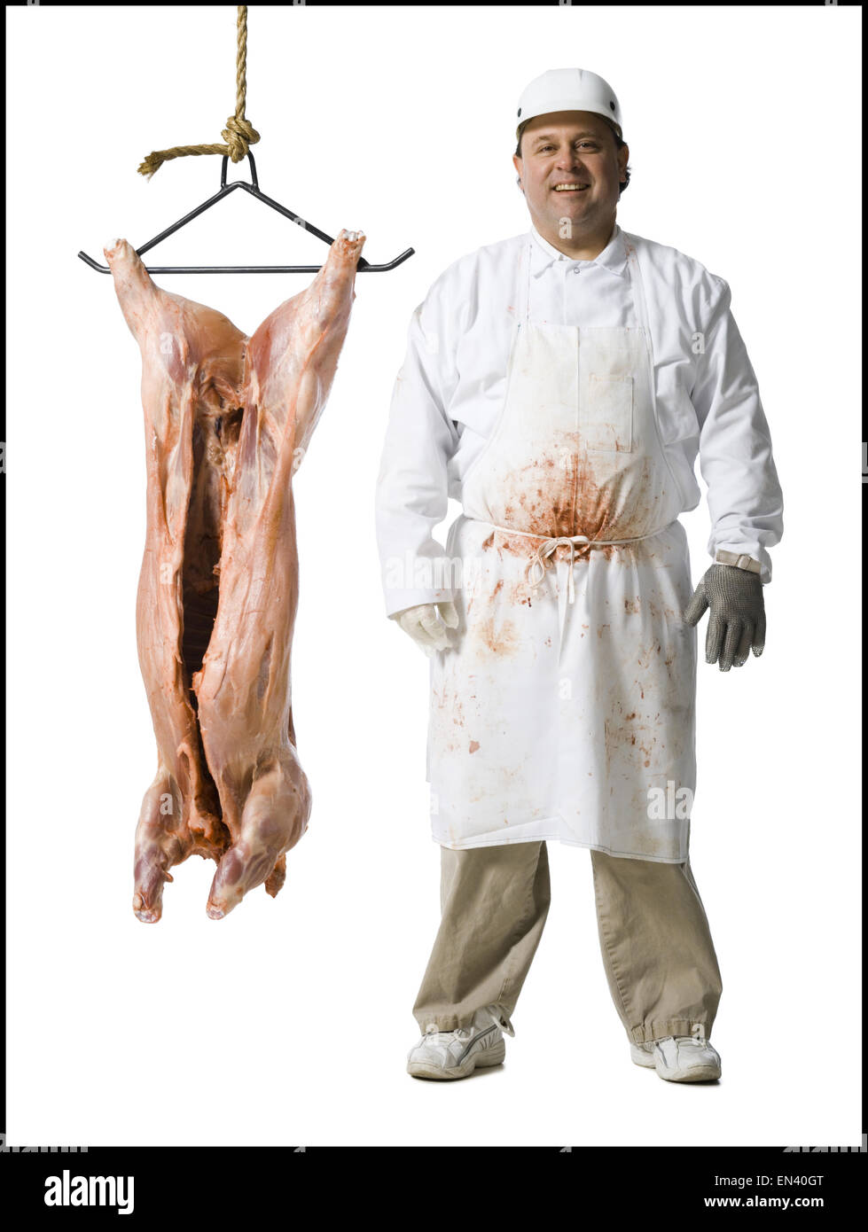 El carnicero de pie con la cuchilla y carcasa colgante Foto de stock