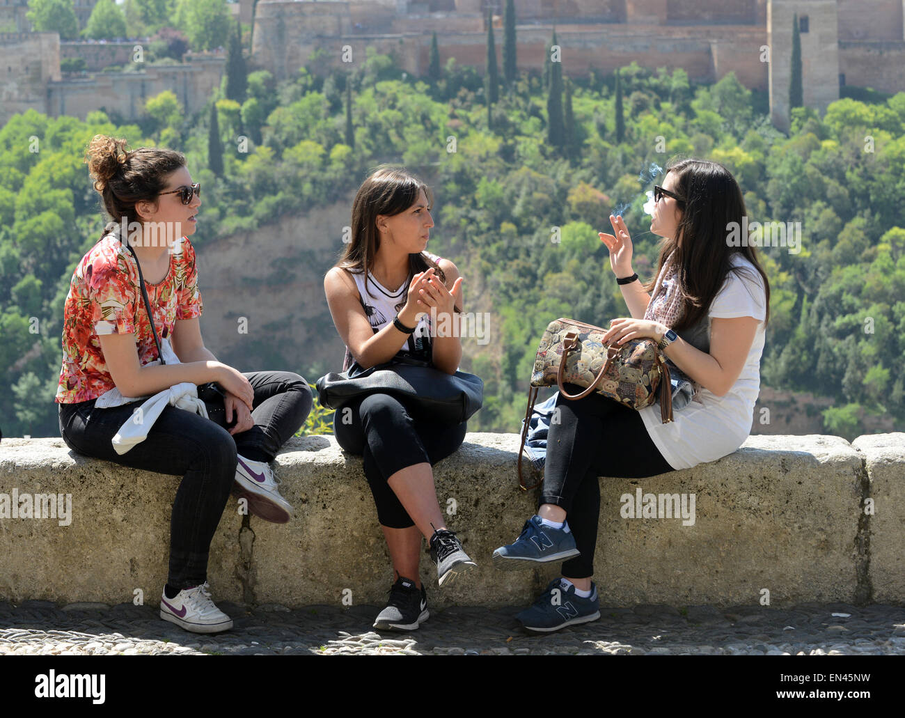 Chicas mujeres mujeres sentadas hablando y fumando en Granada España Foto de stock
