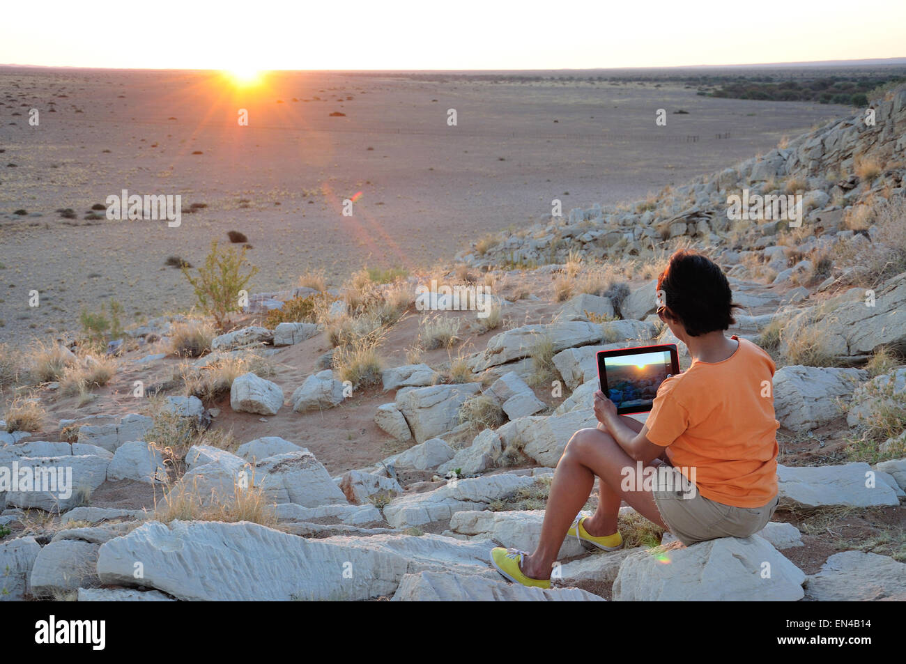 Mujer fotografiando atardecer con ipad en el desierto de Namib, Solitario, desierto de Namib, República de Namibia Foto de stock