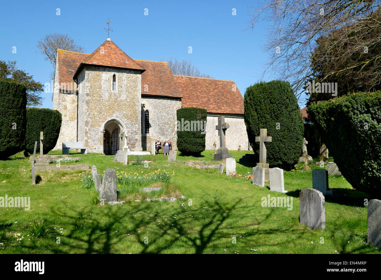 Dos ancianos sentarse fuera de la iglesia parroquial de St Andrew's, en el oeste de Stoke, West Sussex, Inglaterra Foto de stock