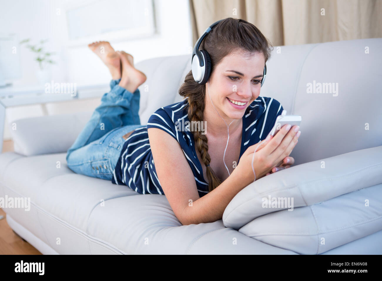 Hermosa morenita escuchando música con su smartphone Foto de stock