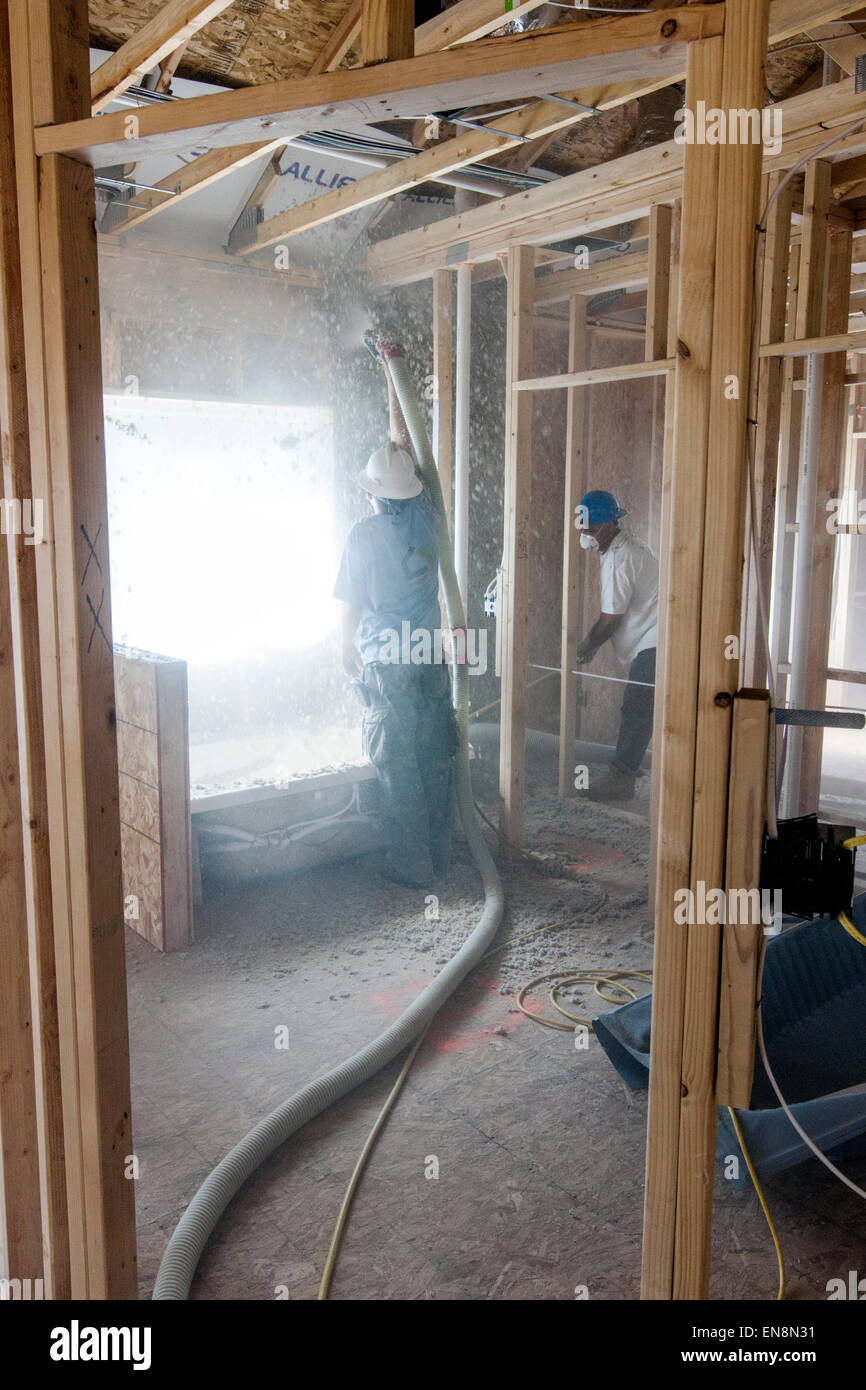 Los trabajadores rociando aislamiento de celulosa en las paredes de una casa nueva en construcción Foto de stock