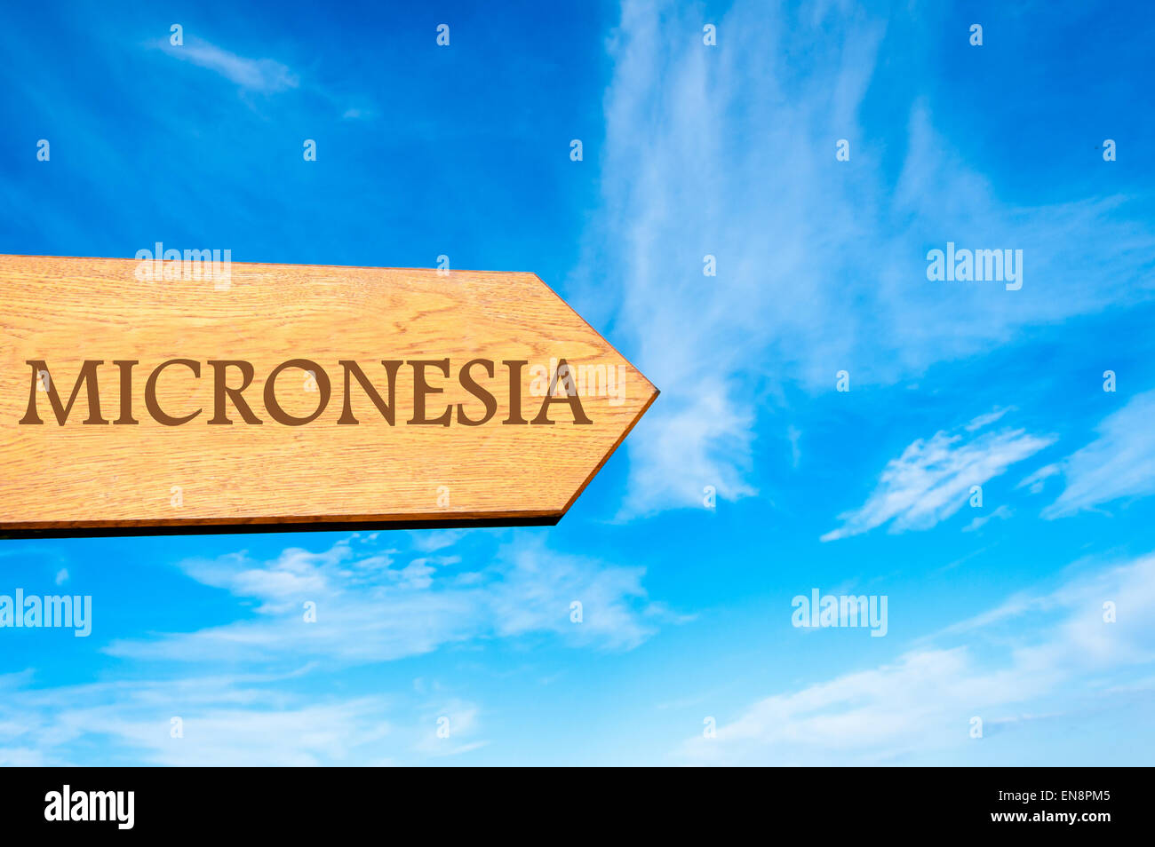 Signo de flecha de madera apuntando destino Micronesia contra el cielo azul claro con copia espacio disponible. Imagen conceptual del destino de viaje Foto de stock