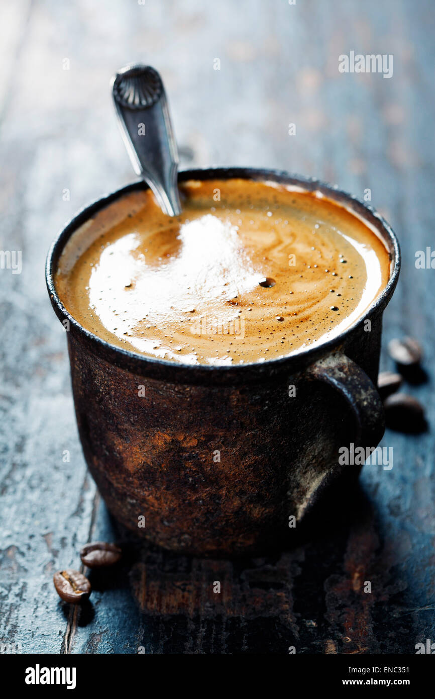 Antigua taza de café oscuro sobre fondo rústico Foto de stock